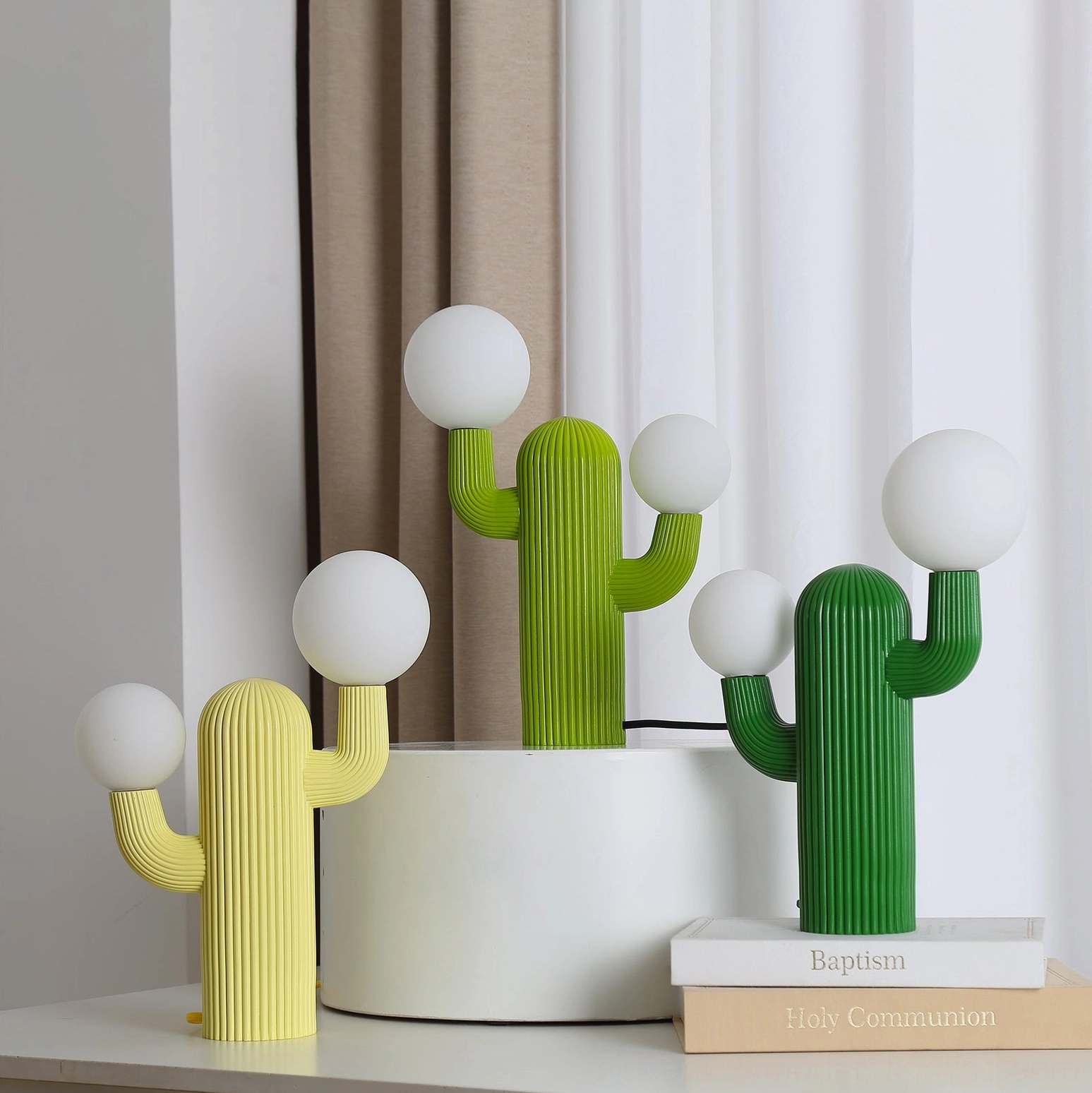 Cactus table lamps styled on bedroom nightstand with stacked books and curtain backdrop, showing multiple design styles