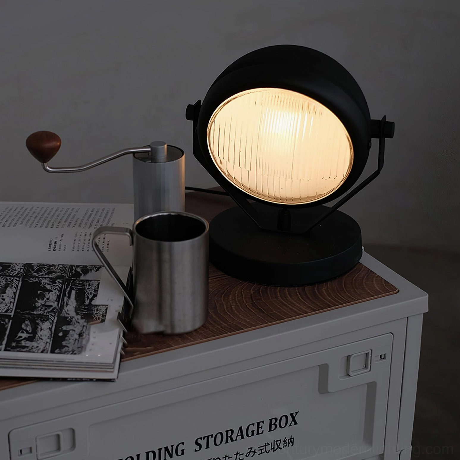 Illuminated Cadillac matte black round table lamp on storage box with coffee utensils, warm indoor lighting ambience