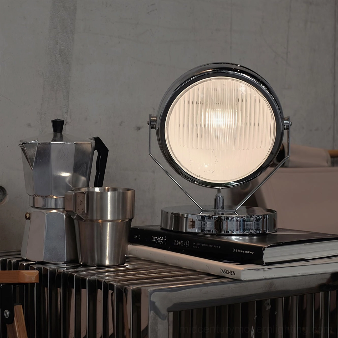 Illuminated Cadillac chrome spotlight lamp casting warm light in industrial coffee setting with vintage accessories