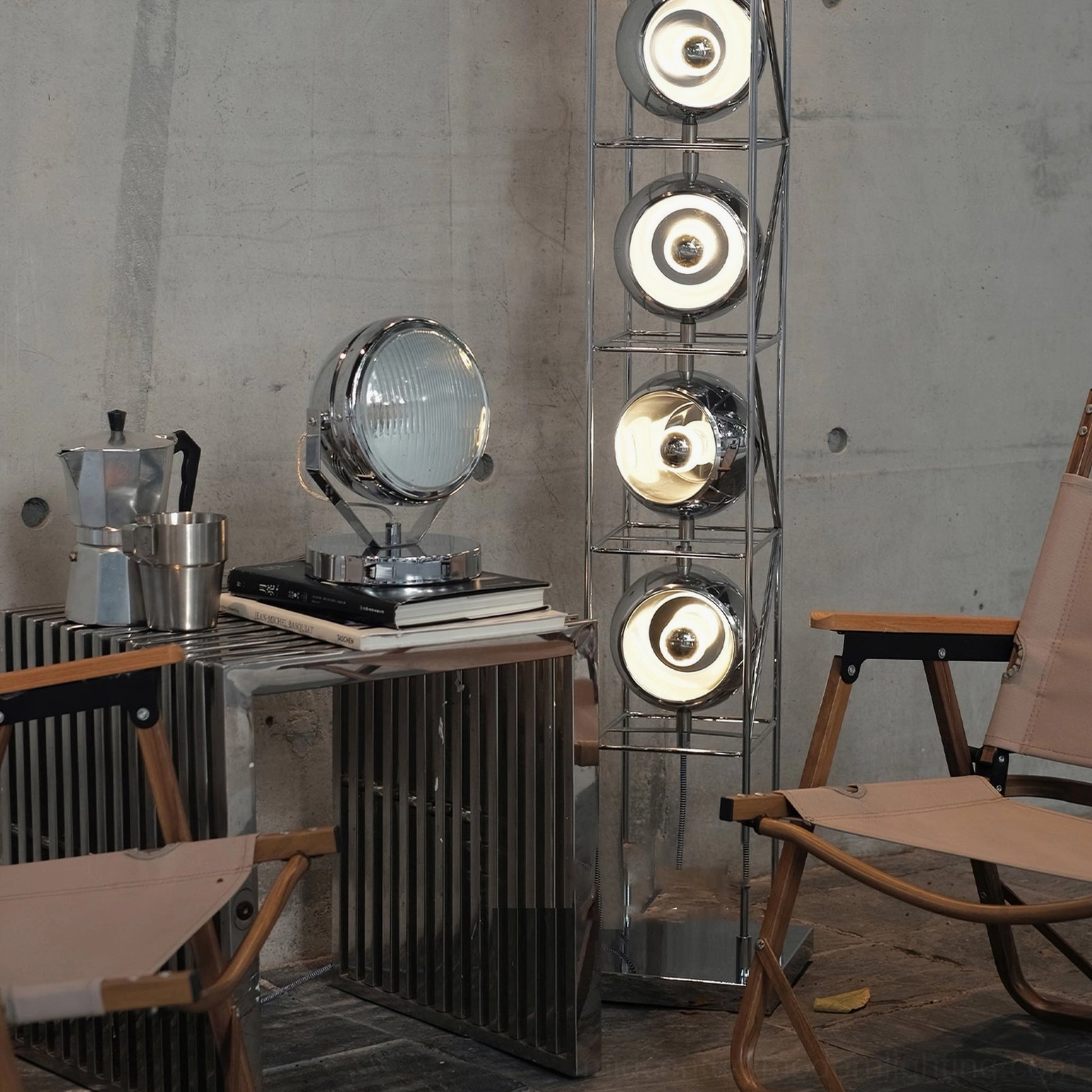 Cadillac chrome industrial spotlight lamp in loft living space with folding chairs, concrete walls and floor lamp background