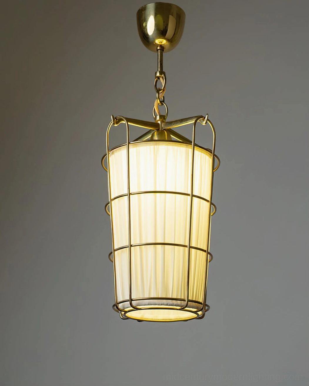 Caged chandelier emitting warm yellow ambient lighting, brass cage frame silhouette on dark background
