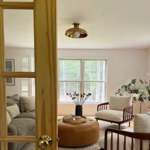 Caldera ceiling light brass gold finish installed in modern living room with glass doors warm ambient glow