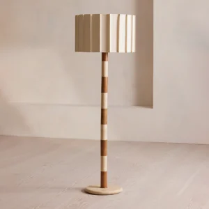 Calypso floor lamp with two-tone striped column in minimalist living room with light wood flooring, brass base and travertine details