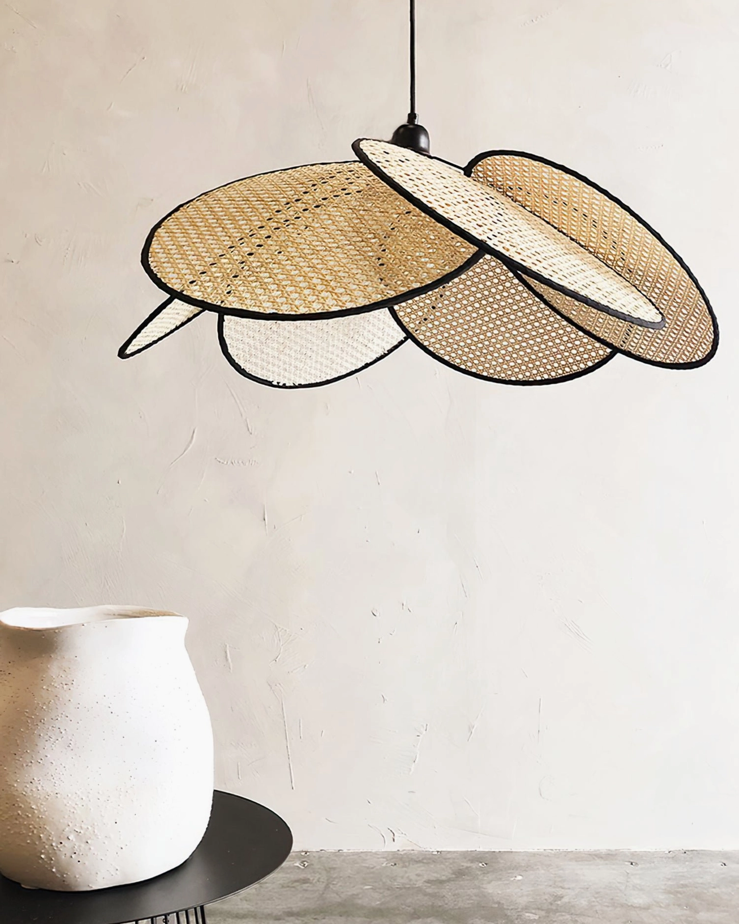 Layered rattan petal pendant design with natural neutral tones displayed against minimalist wall with ceramic vase accent, close-up texture view