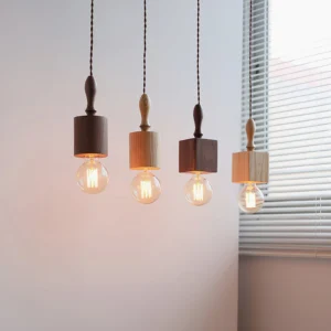 Cluster of four Cano wooden pendant lights in mixed finishes with warm filament bulbs, indoor hanging display