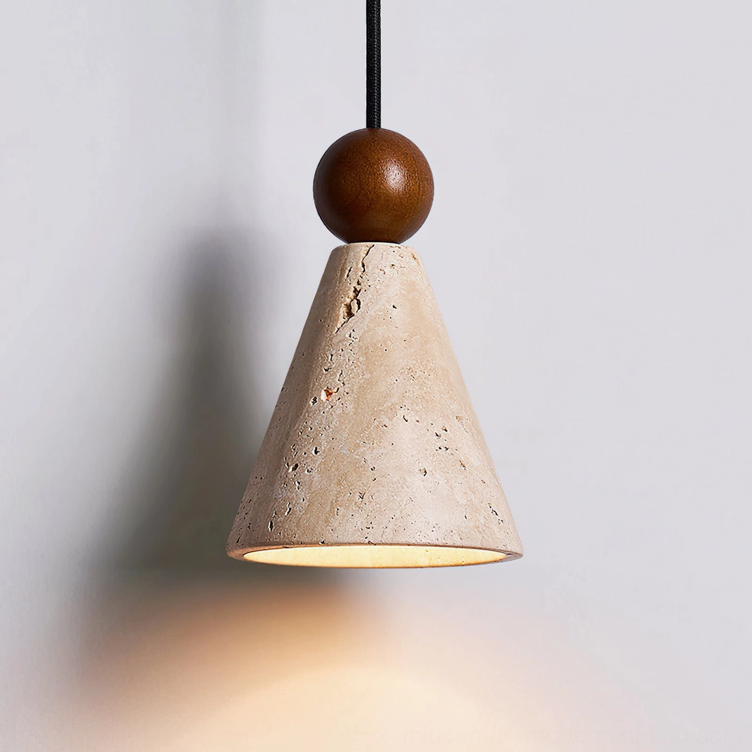 Illuminated travertine pendant light showing natural porous stone texture and warm light diffusion