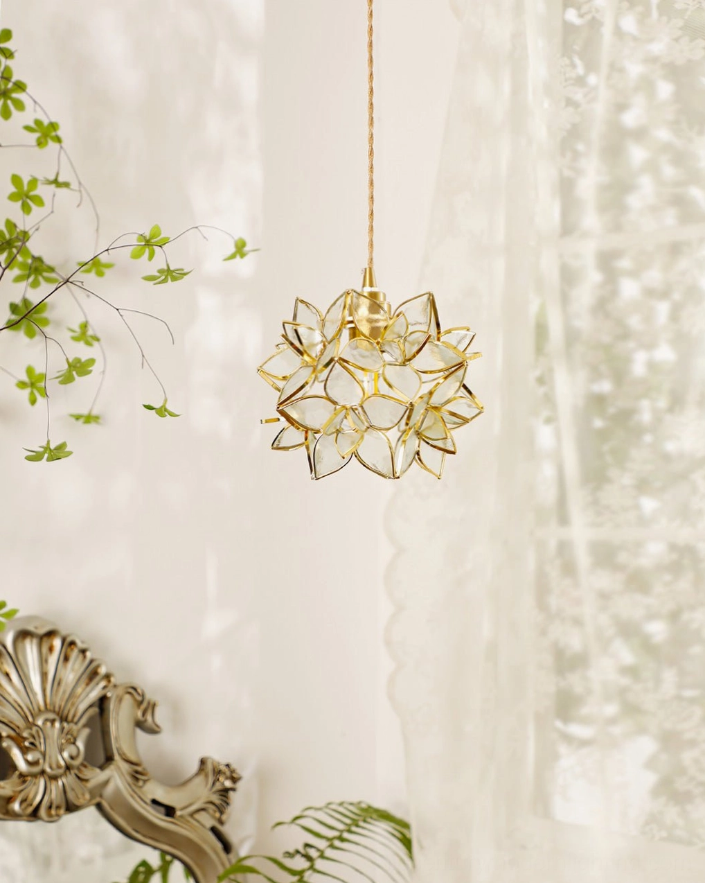 Capiz pendant light installed in side view above table with autumn home decor and greenery styling