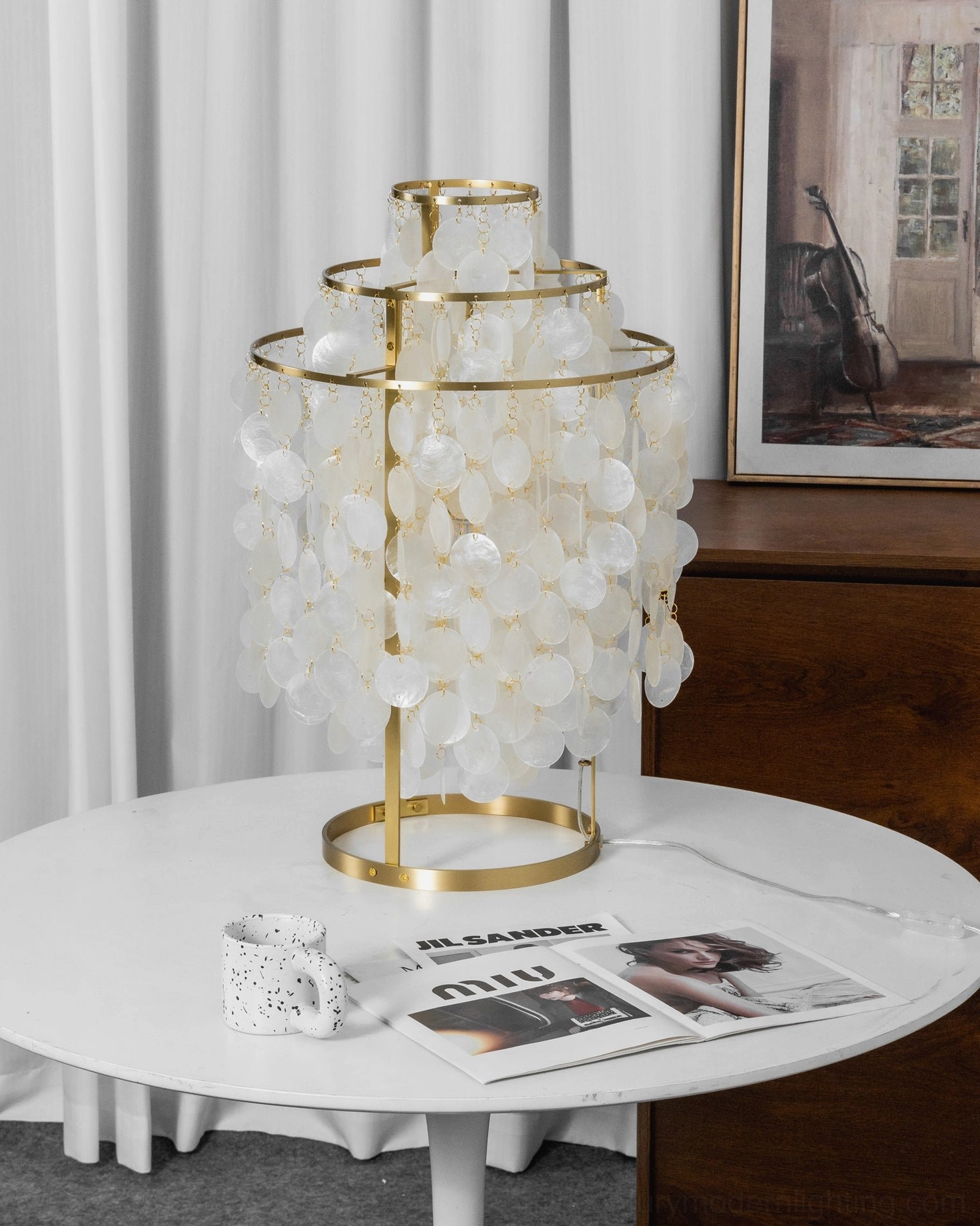 Modern minimalist capiz shell table lamp on home side table with artwork backdrop