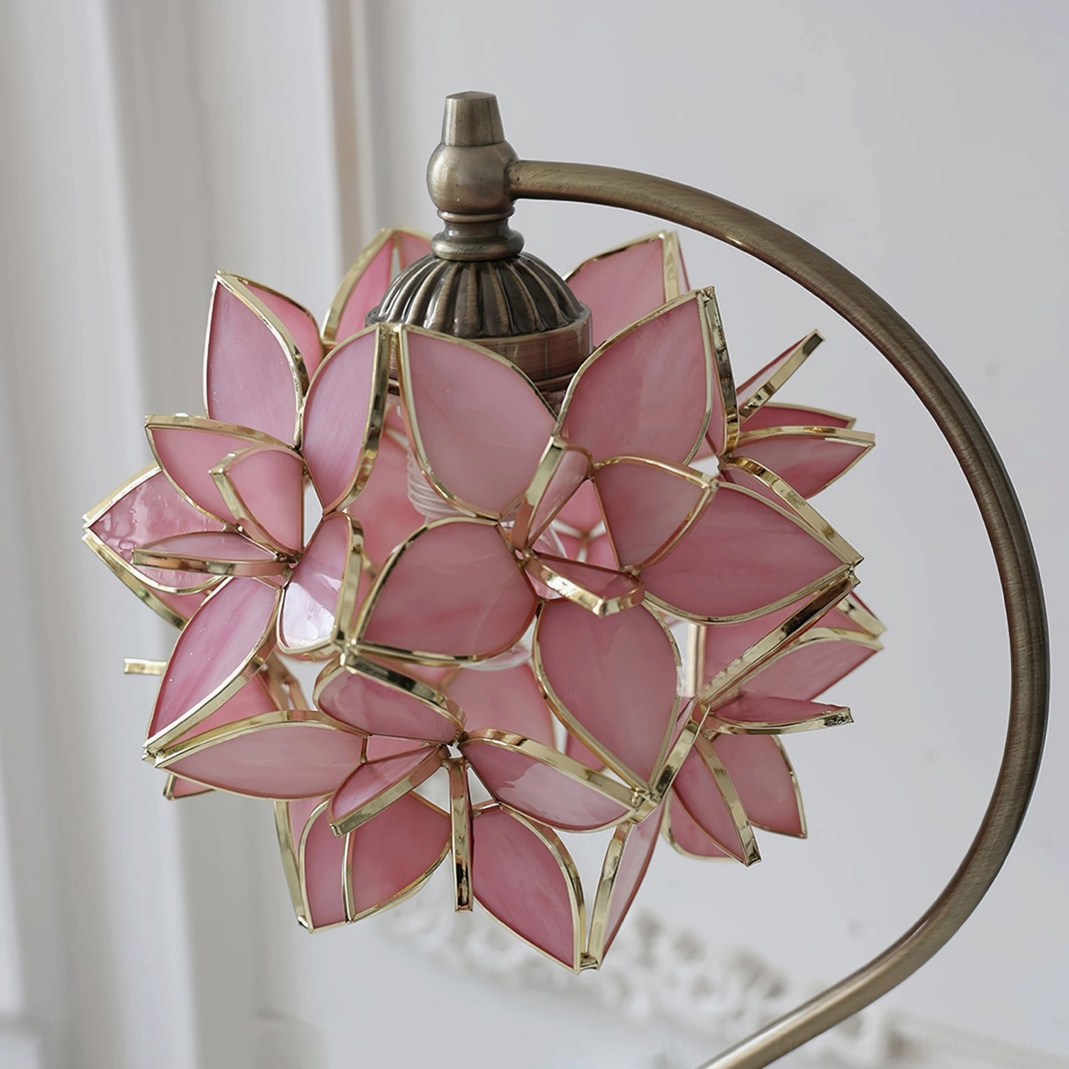 Close-up detail of pink stained glass capiz petals with gold trim and bronze metal fixture, artisanal craftsmanship