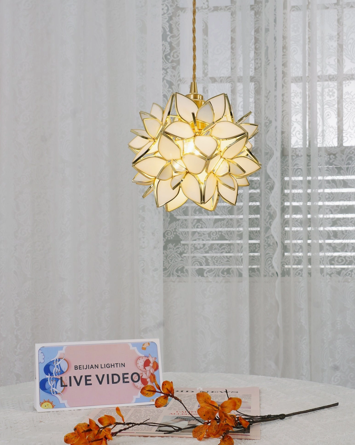 Illuminated Capiz pendant lamp casting warm glowing light through glass petals in home interior setting