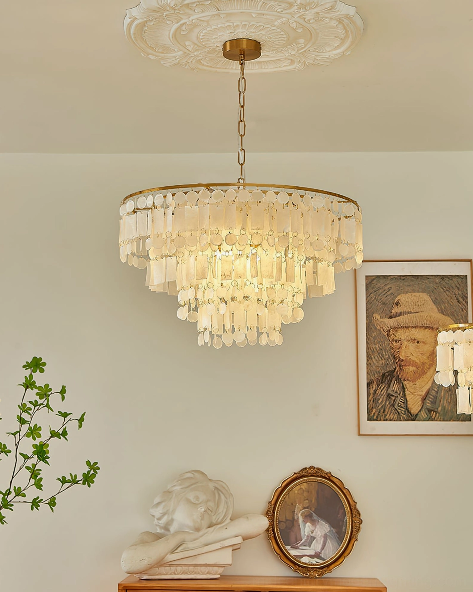Luxury capiz shell chandelier with brass gold hardware in living room with wall art, tiered shell design creating soft diffused light