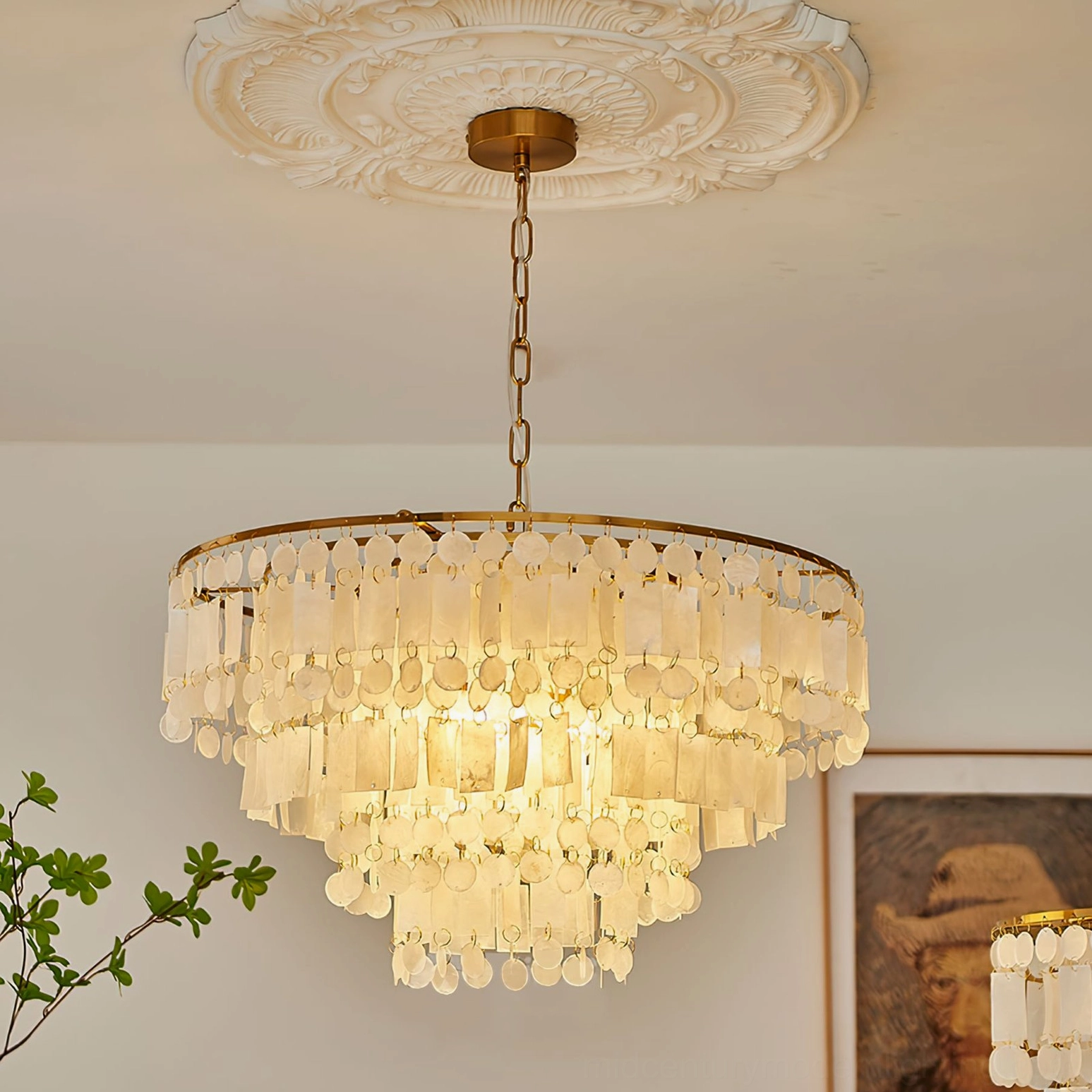Capiz shell chandelier installed in residential room with ceiling medallion, low angle view showing round gold frame and ambient lighting