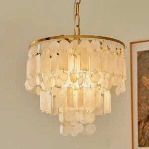 Close-up detail of capiz shell chandelier showing layered creamy shell pendants with warm glowing light and brass hardware