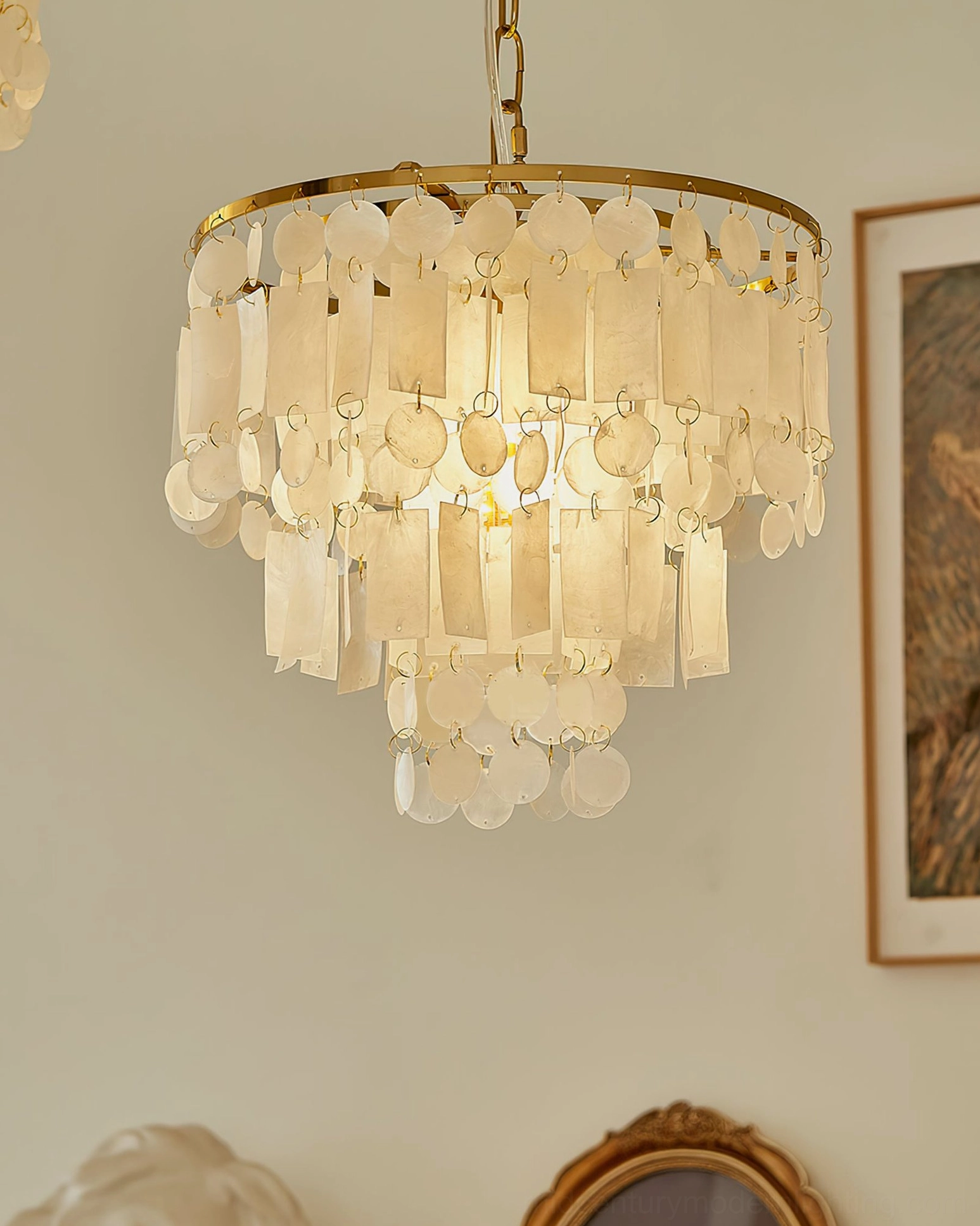 Capiz shell chandelier close-up showing delicate tiered shell pendants with warm luminous glow and refined metalwork