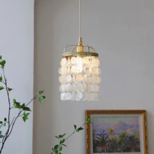 Capiz shell pendant hanging in modern living room with green plants and framed wall art showcasing translucent shell design