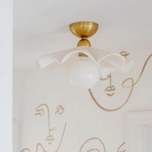 Capri flush mount ceiling lamp installed in modern bedroom with textured wallpaper and warm brass hardware accent wall