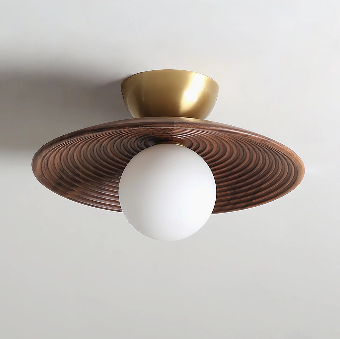 Close-up side angle of Carapace flush mount light showing brushed brass ceiling cap and detailed concentric ribbed texture