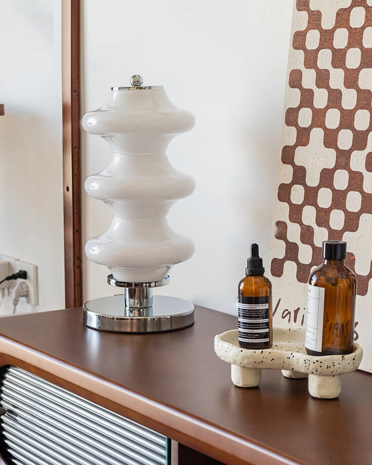 Carlo midcentury lamp on wooden desk workspace paired with skincare items and checkered wall art styling
