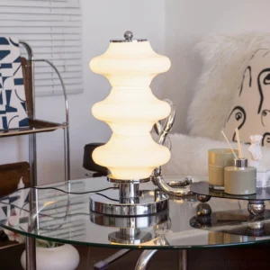 Lit Carlo table lamp glowing warmly in modern dining room with polished chrome accents and layered glass diffuser