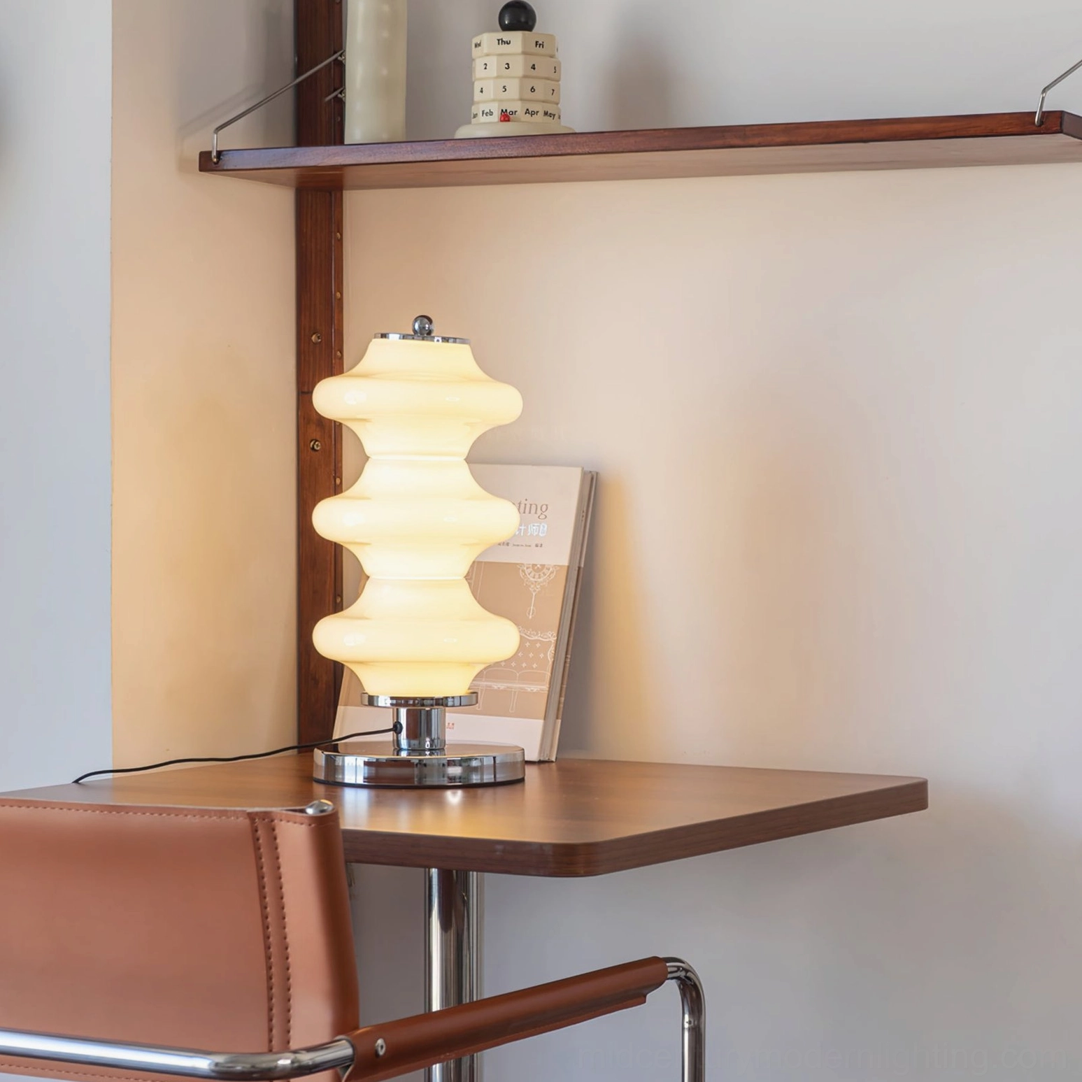 Lit Carlo table lamp three-quarter view providing warm ambient lighting in small home study corner with wooden desk