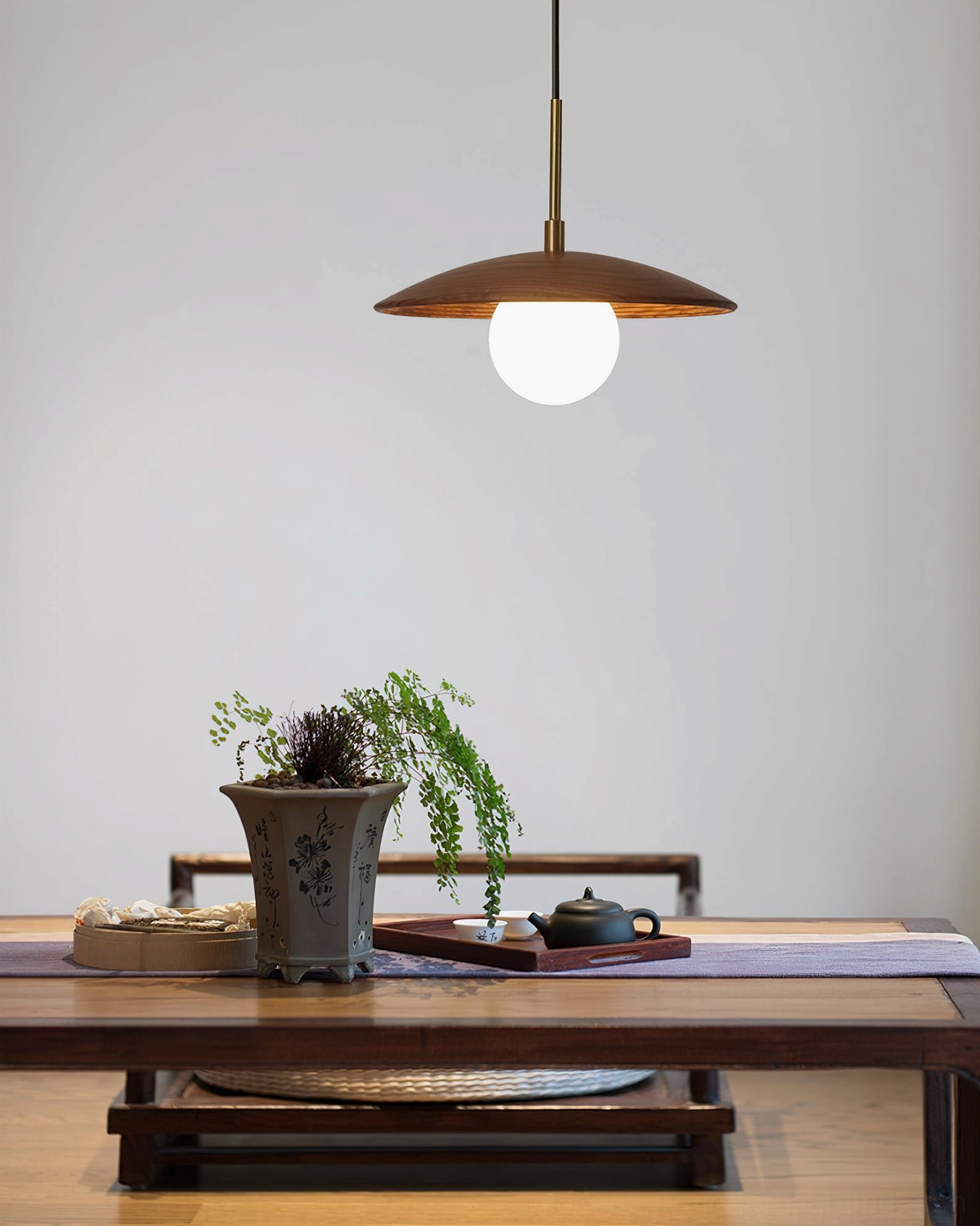 Single Caroll saucer pendant light above wooden table in chinese-style minimalist interior