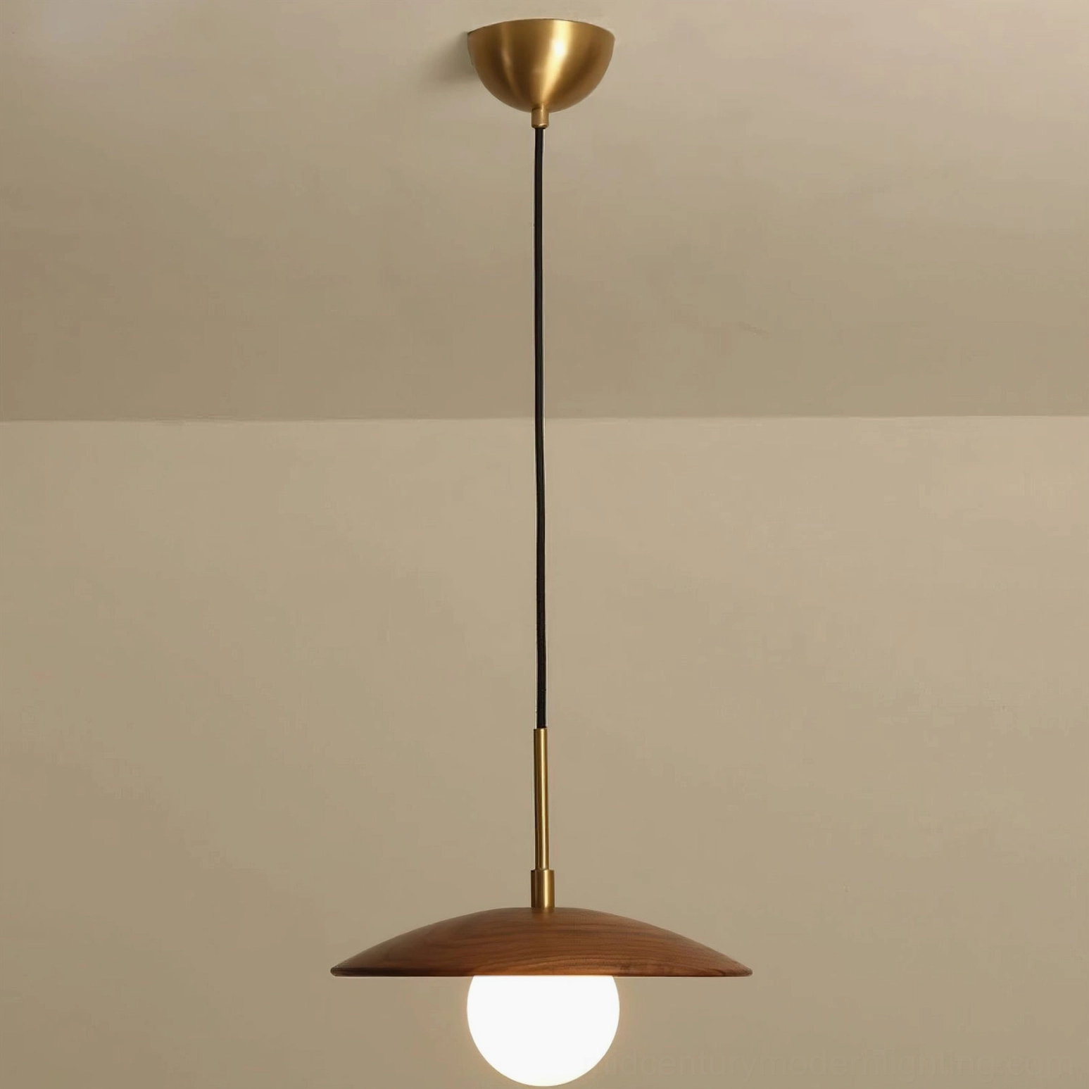 Caroll walnut and brass pendant fixture illuminated showing warm light diffusion through frosted globe
