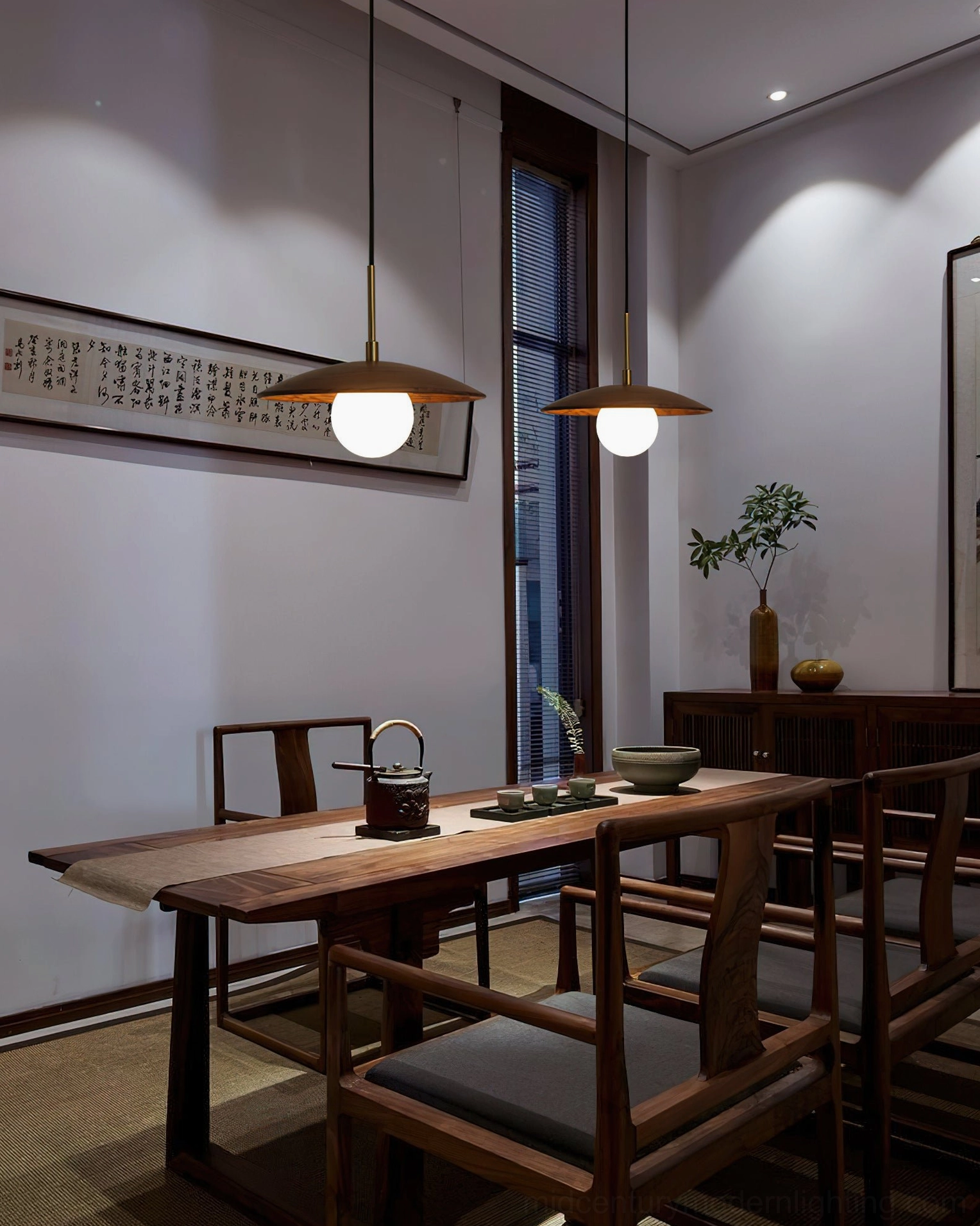 Two Caroll walnut and brass pendant lights in chinese-style dining room above wooden dining table