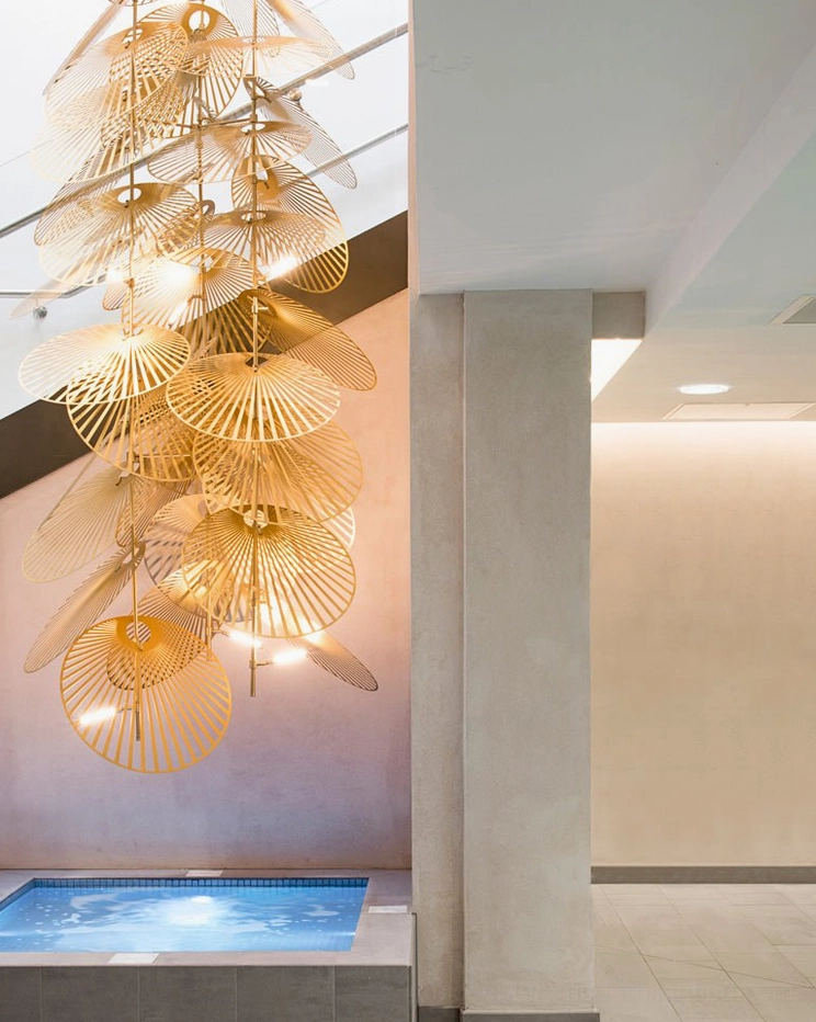 Large vertical cascade fan chandelier low angle view in spa relaxation area with brushed gold finish