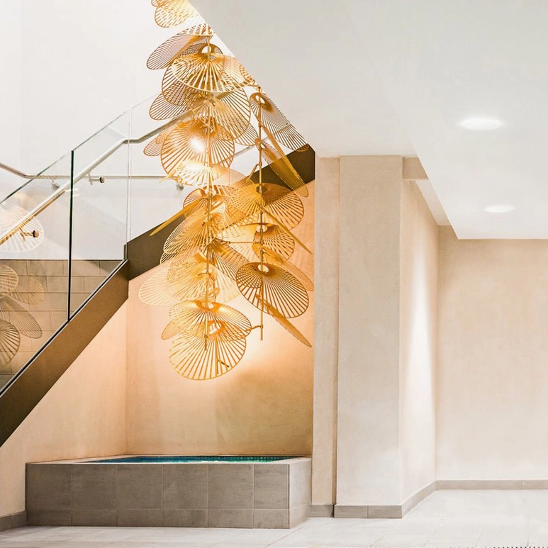 Long vertical cascade fan chandelier low angle view in duplex stairwell with swimming pool setting