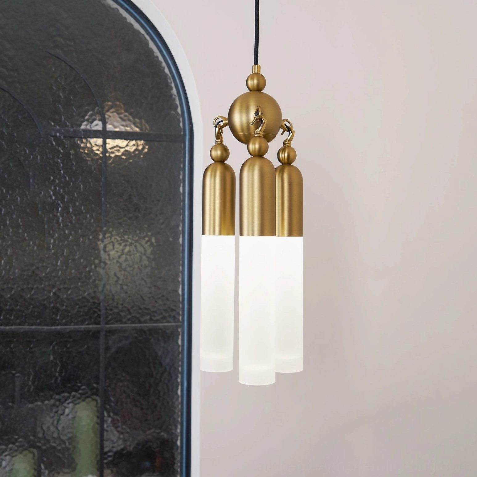 Cascadia brass pendant illuminated close-up showing premium metal hardware and bright frosted acrylic glass details