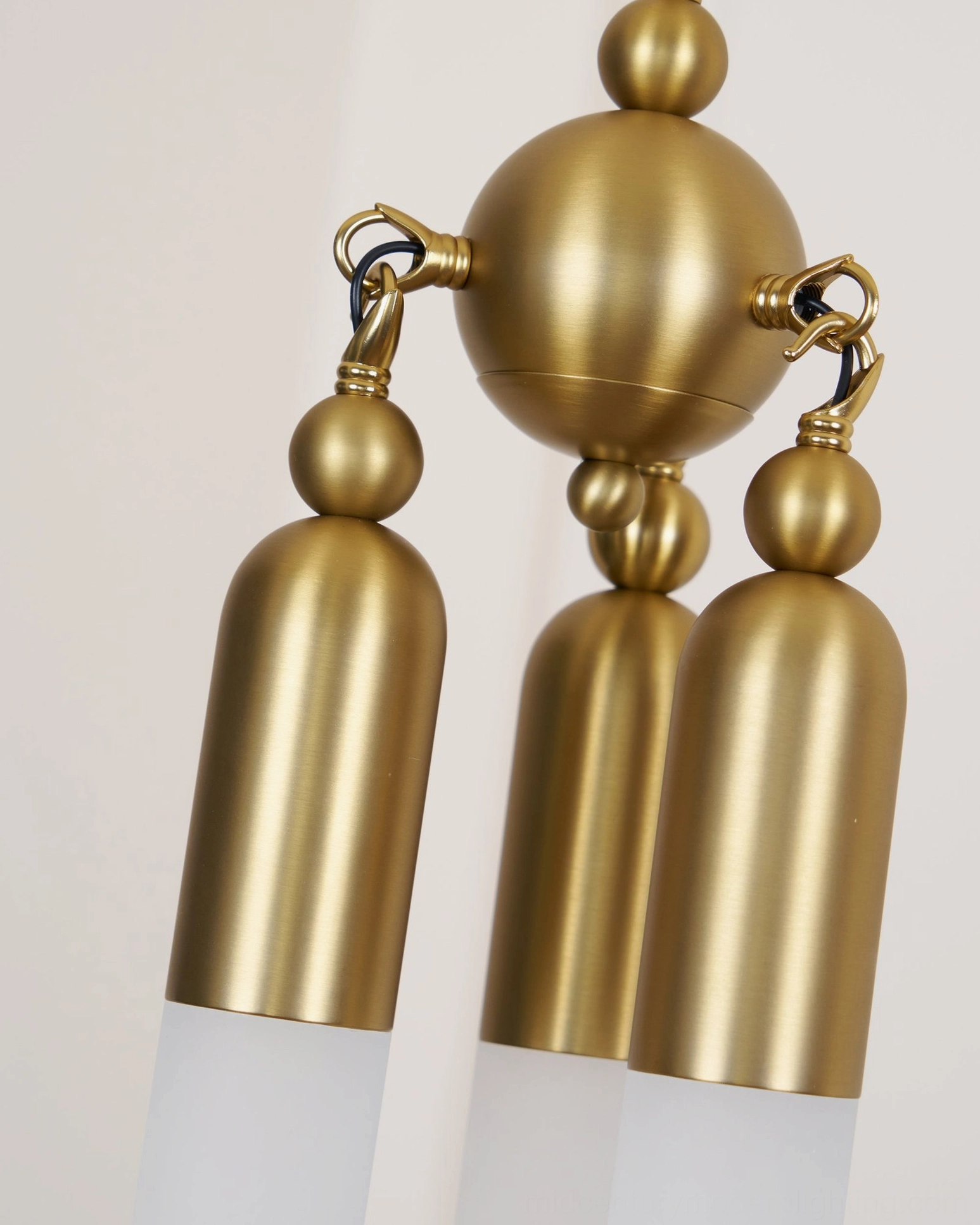 Side close-up of Cascadia pendant showing brass lamp caps, glass sleeves, and spherical mounting architecture