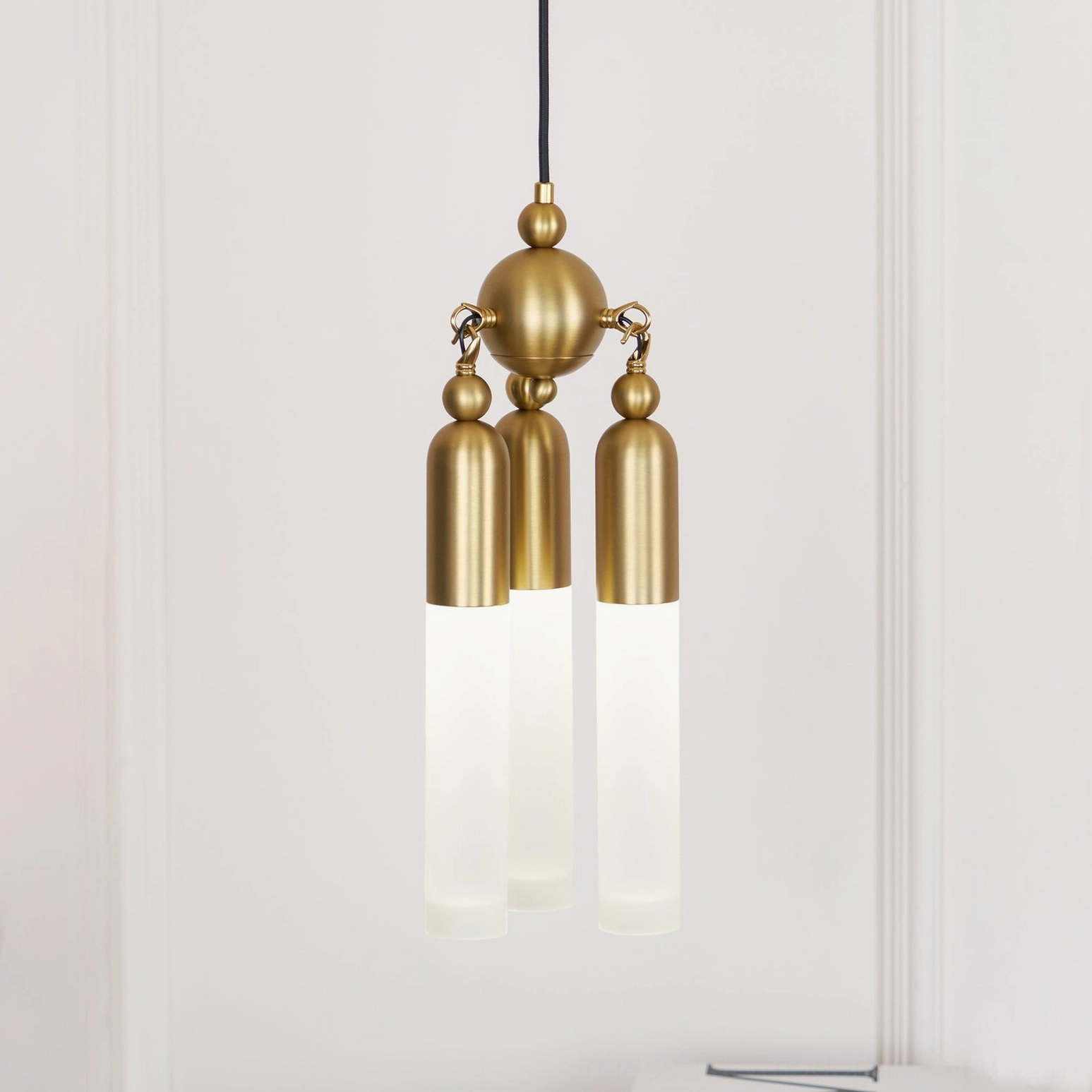 Close-up of Cascadia pendant light showing warm LED illumination through frosted acrylic shades and brass suspension hardware