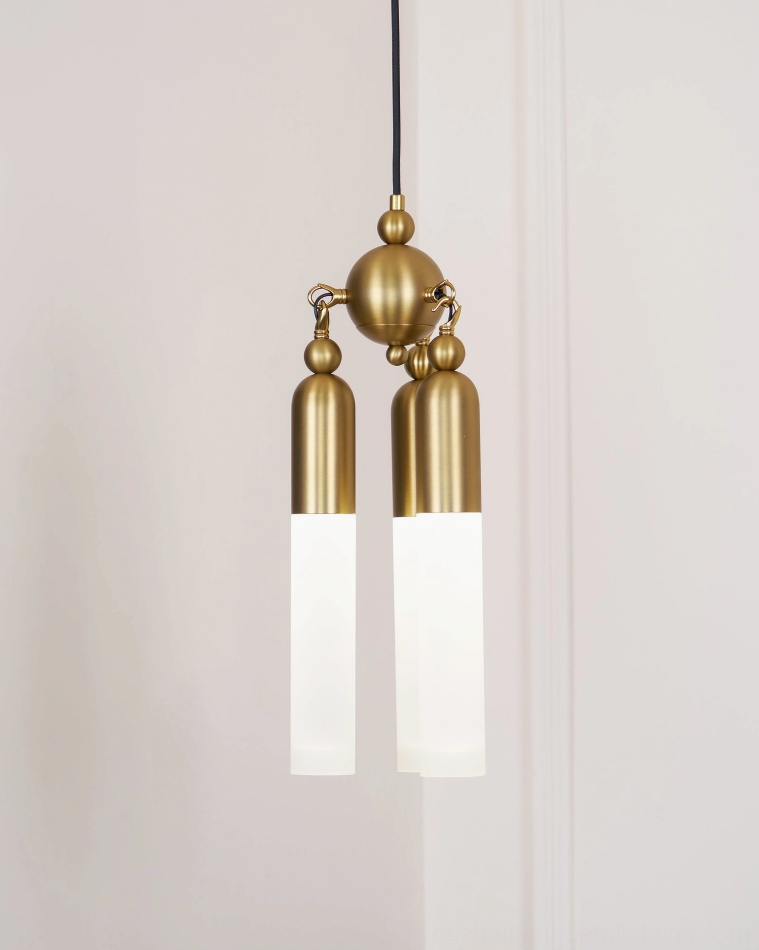 Cascadia two-light brass pendant with fully illuminated frosted glass shades against minimalist white interior wall