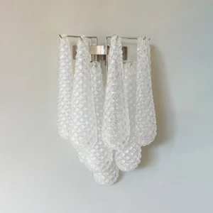 Mid-century modern glass wall sconce mounted on light gray wall, close-up showing drooping petal glass shades