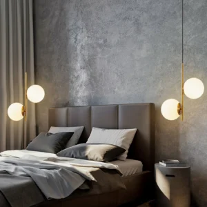 Castell dual globe pendant lamp with brass finish suspended in luxury modern bedroom above tufted leather headboard creating warm ambient lighting