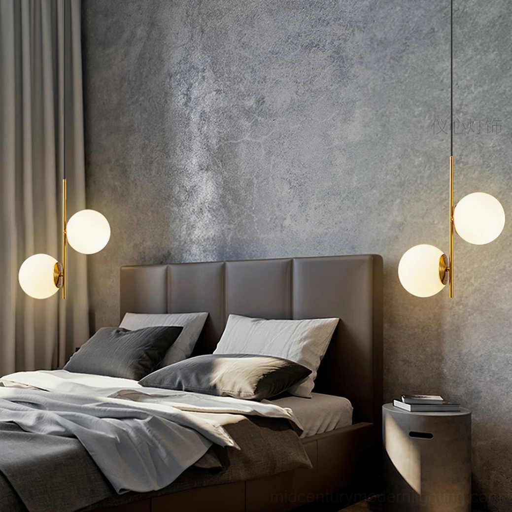 Castell dual globe pendant lamp with brass finish suspended in luxury modern bedroom above tufted leather headboard creating warm ambient lighting