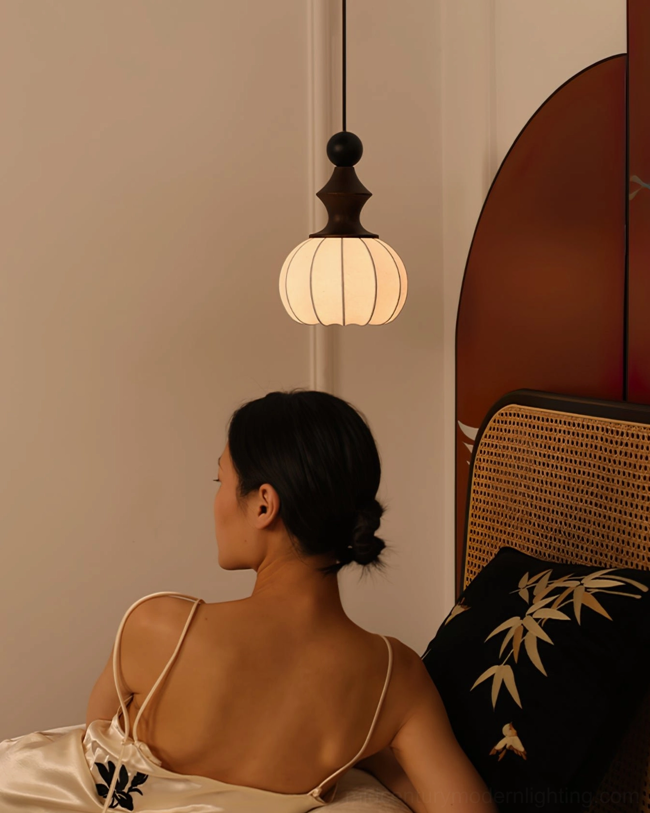 Castiglioni pendant light illuminated in elegant French vintage-inspired bedroom with rattan headboard and refined mid-century décor