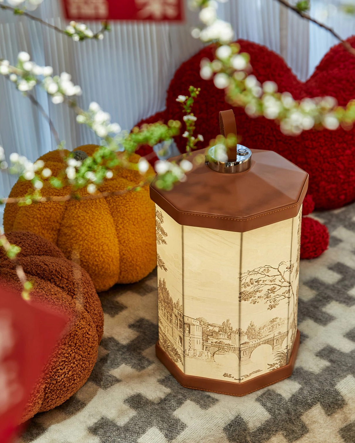 Lit Castle landscape print table lamp displayed at high angle on festival home floor with plush pumpkin cushions and flowering branches, seasonal home decor styling