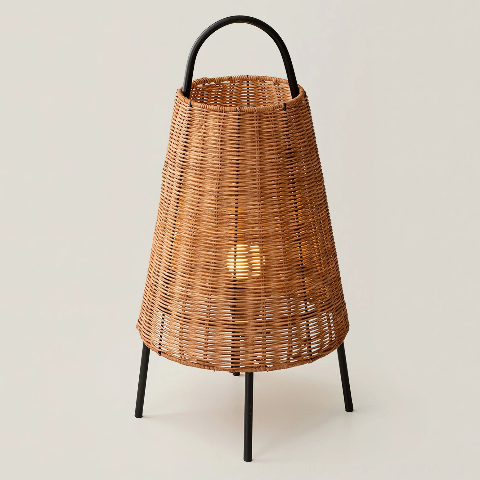Catalina Coastal Table Lamp glowing from within, clear view of rattan weave and geometric black metal tripod frame