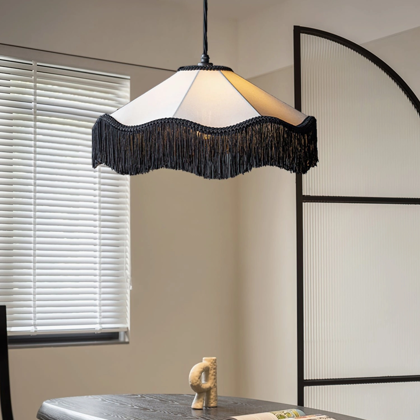 Cecile Tassel Pendant Lamp suspended in minimalist dining room with window blinds, showing wavy fabric shade and black tassel edge decoration