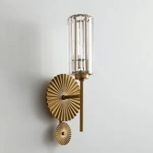 Cecily wall sconce three-quarter angle displaying ribbed crystal glass shade and brass mounting plate on neutral background