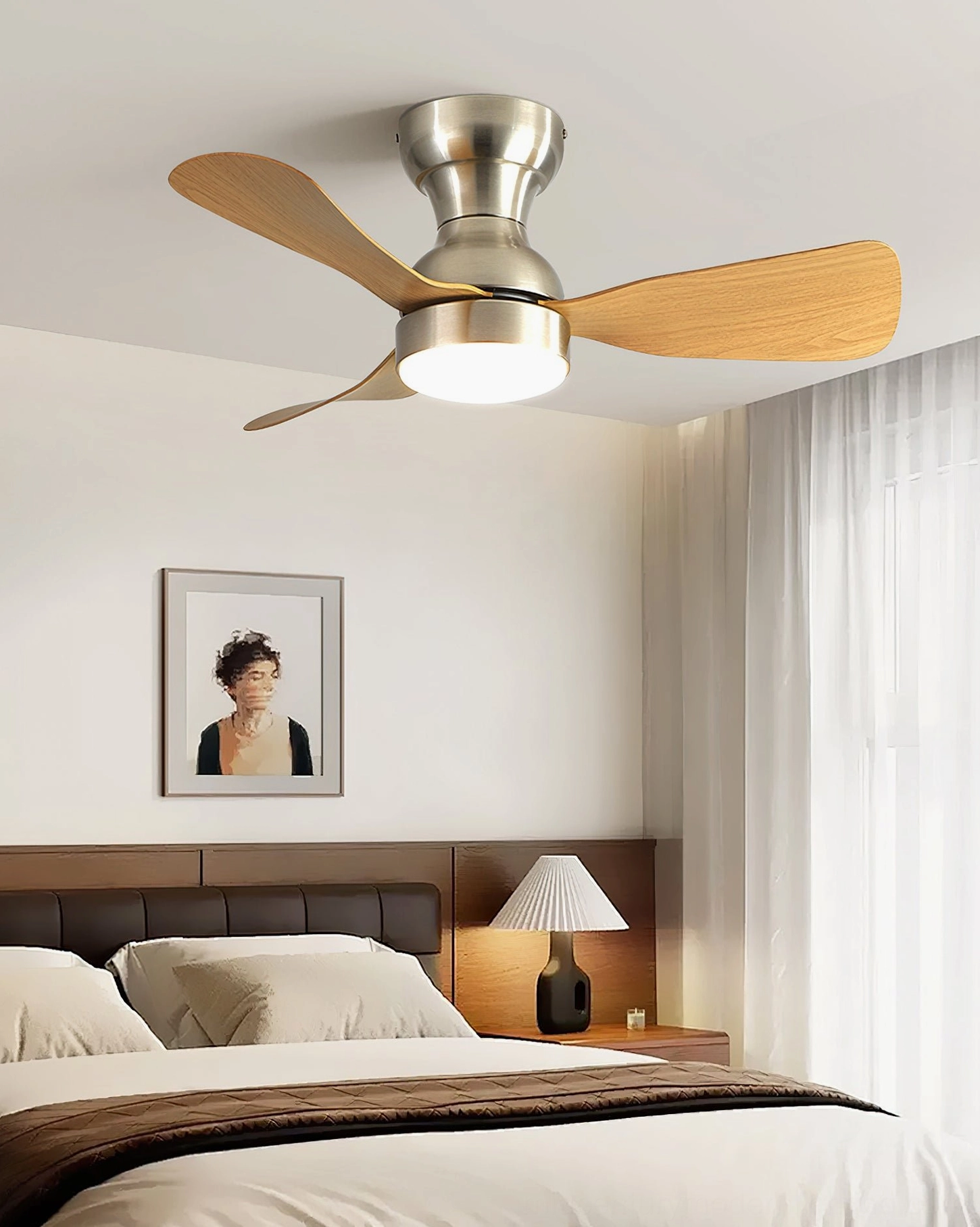 Modern bedroom with integrated LED ceiling fan light installed above neutral bedding, low-profile flush mount with light wood blades in contemporary interior