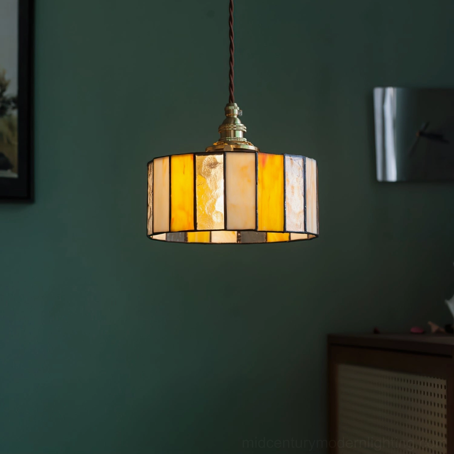 Warm stained glass drum pendant ceiling light with diffused amber glow, vintage Tiffany-style brass mounting