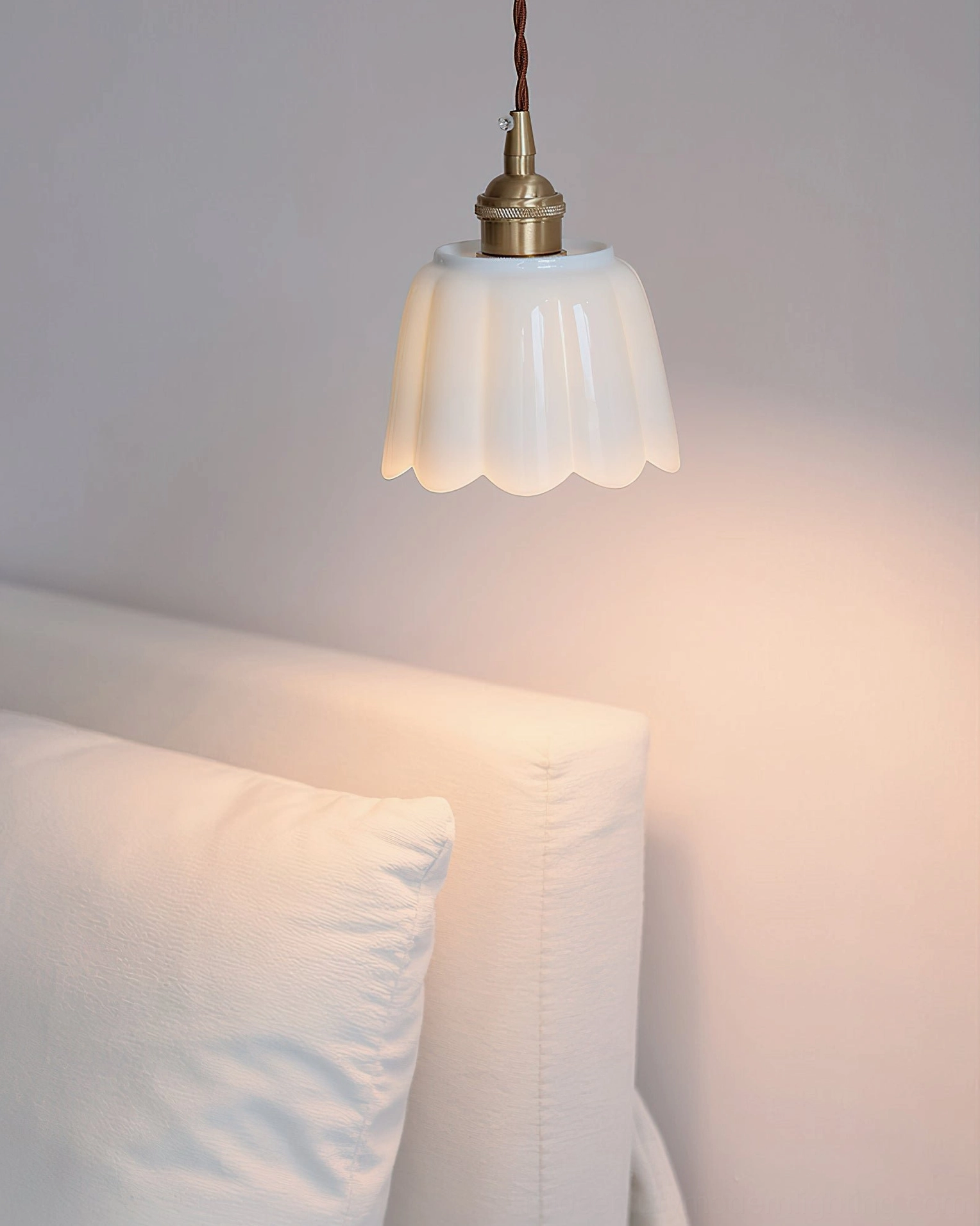 Celadon pendant light illuminating bedroom bedside area with soft warm ambient glow