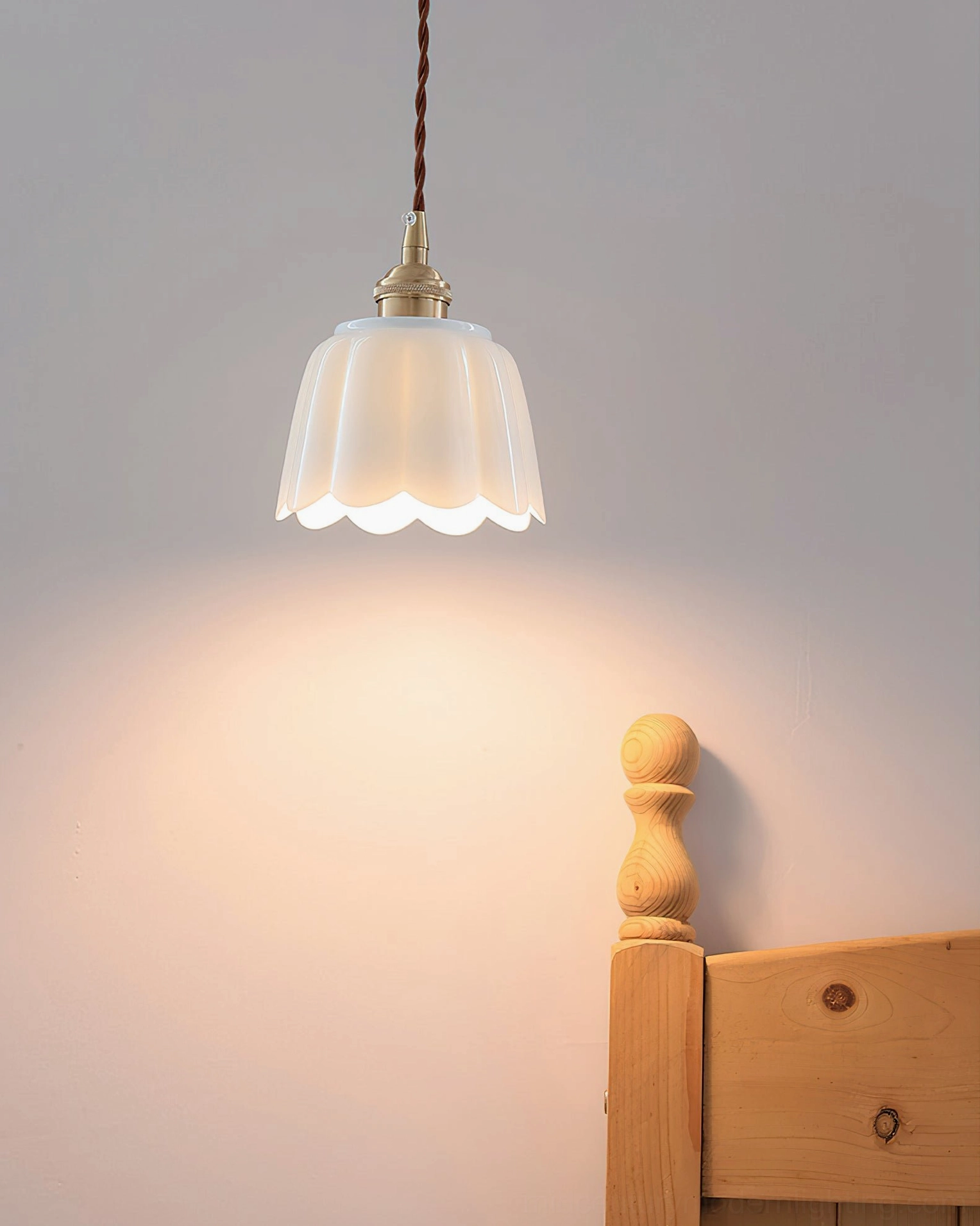 Celadon fluted ceramic pendant casting warm light effect on bedroom wooden headboard wall