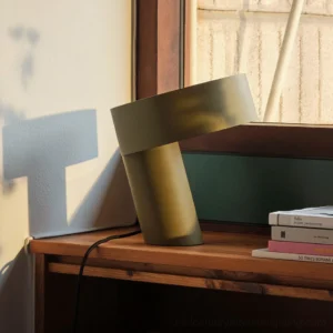 Celia table lamp khaki green on wooden window sill, casting geometric shadow on wall, contemporary interior styling