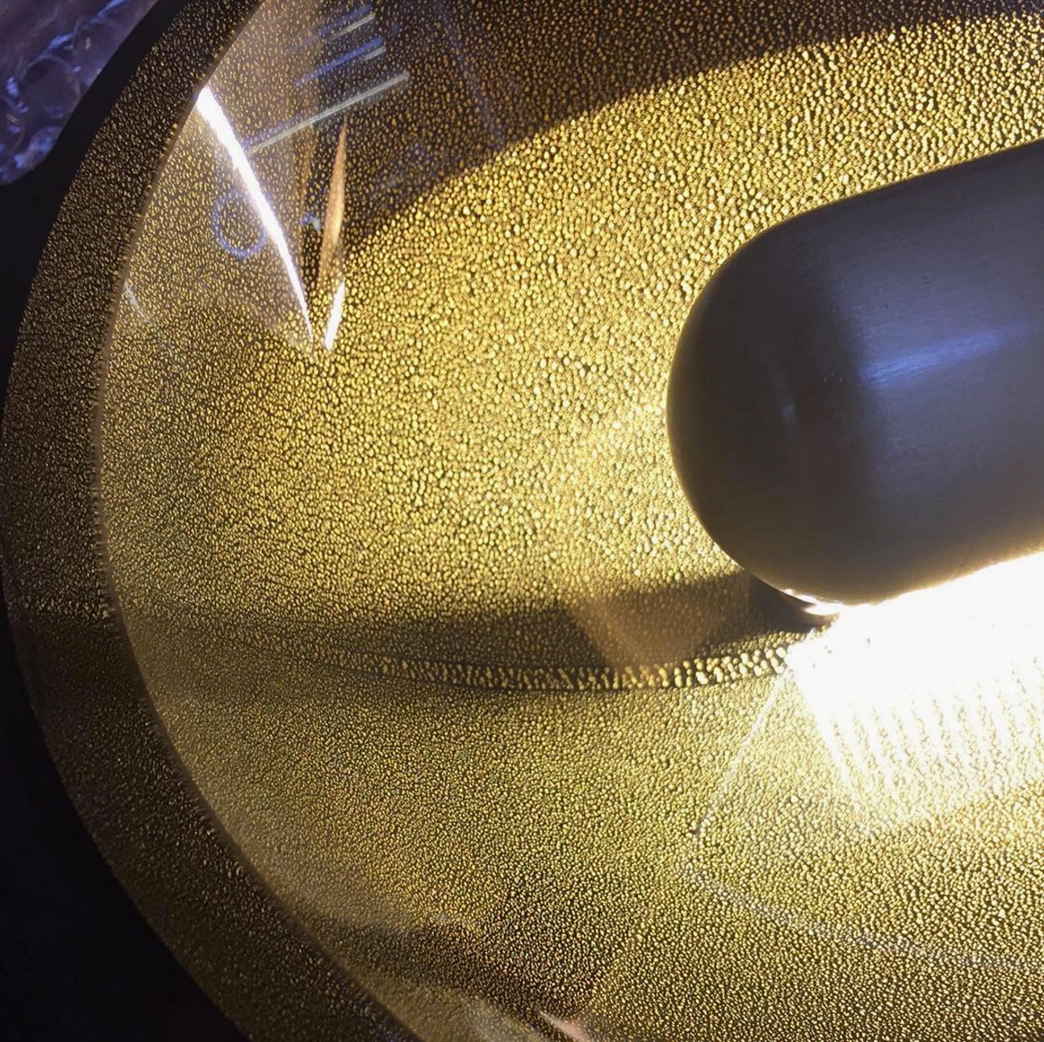Cell Wall Lamp shade close-up detail showing etched brass layers and frosted amber glass texture from overhead angle