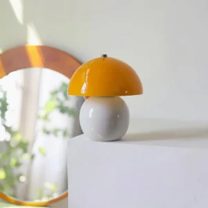 Mushroom ceramic table lamp three-quarter side angle on white platform with wooden mirror backdrop, showing sculptural form