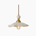 Hand-sculpted white ceramic pendant lamp with brass hardware and ruffled petal-shaped shade, studio front view