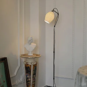 Modern arc floor lamp with black metal frame and warm yellow ribbed fabric shade in classic European interior setting